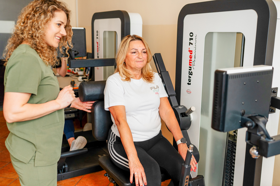 Pacjentka ćwiczy na przyrządach rehabilitacyjnych na siłowni.